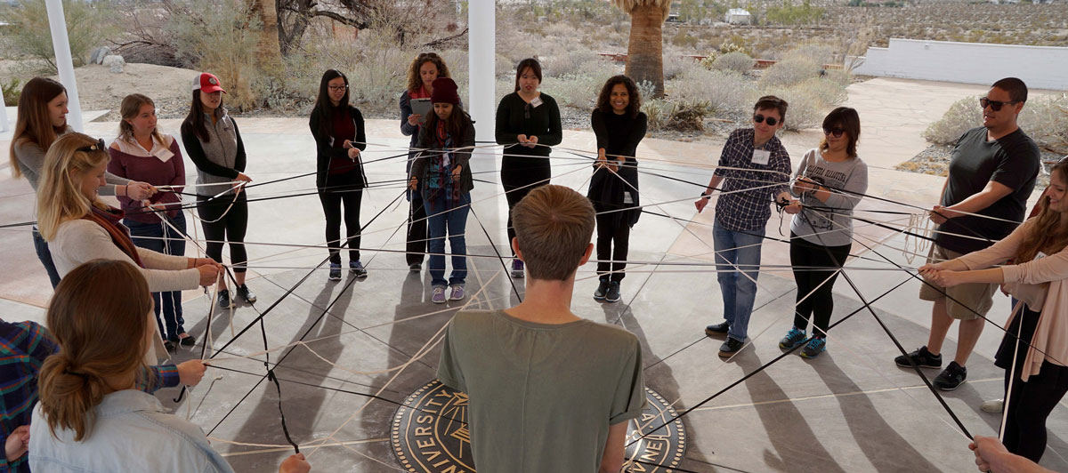 a group of students stand in a circle with yarn